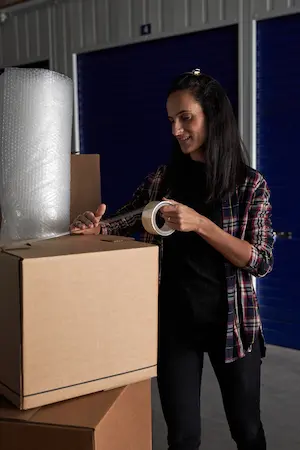 A focused woman efficiently packing and organizing her belongings into a storage unit, demonstrating effective space utilization techniques.